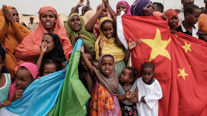 People hold Chinese and Djiboutian national flags at a housing project financially supported by China Merchants Group