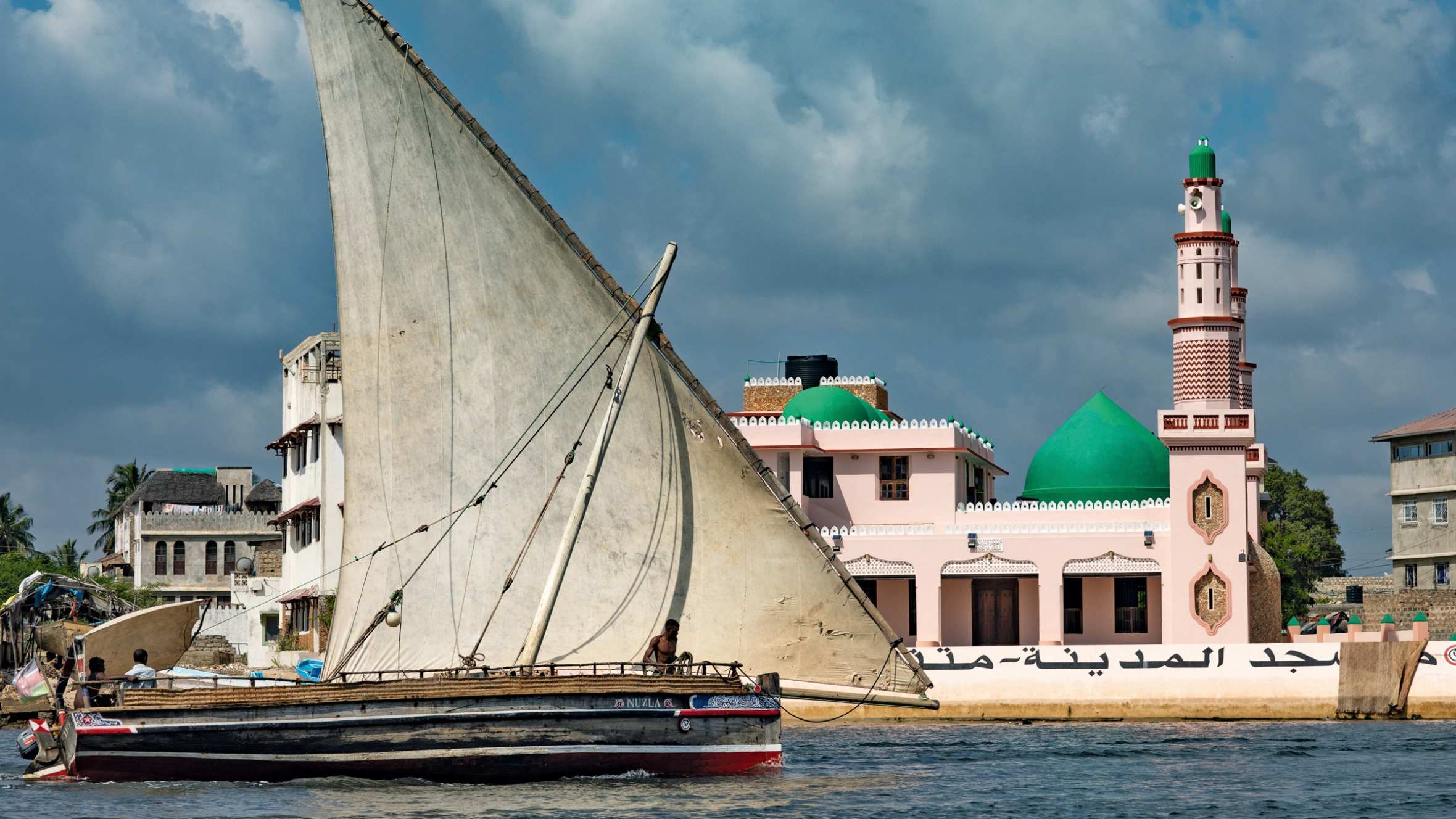 A lateen-rigged dhow boat in front of the Riyadha Mosque