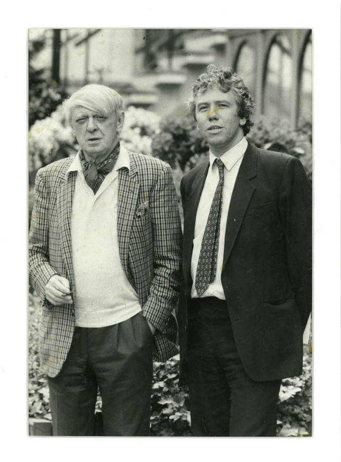 Writer Anthony Burgess, in a jacket and tie, stands next to a John Walsh in a suit 