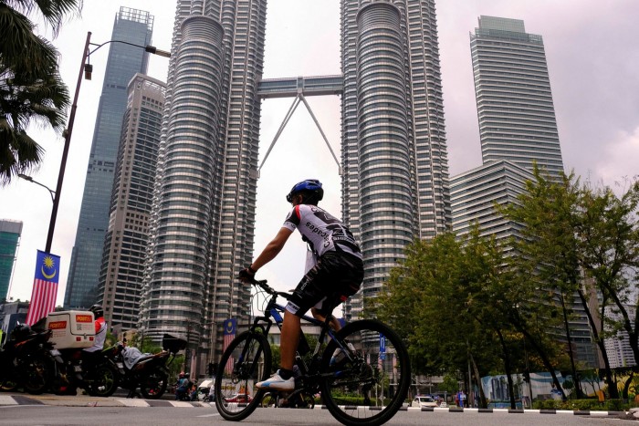 A cyclist cycles past the twin tower headquarters of Petronas in Kuala Lumpur