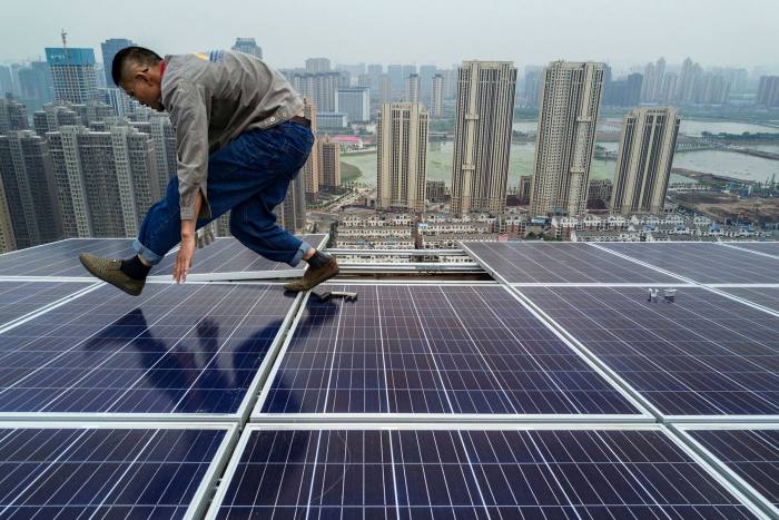 A Chinese worker walks on solar panels on a building in Wuhan. Twenty-two months after the coronavirus pandemic exploded from the province, just as much of the rest of the world reopens and reconnects, China is charting a different course