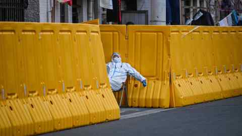 Un trabajador pandémico vigila la entrada a un barrio acordonado en Shanghái en marzo de 2022