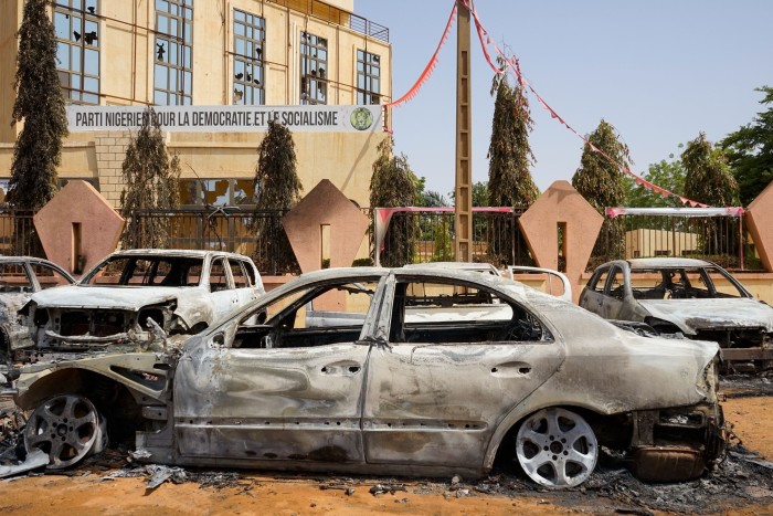 Torched cars sit in front of the headquarters of the Nigerian Party for Democracy and Socialism, which was damaged during anti-government protests in Niamey
