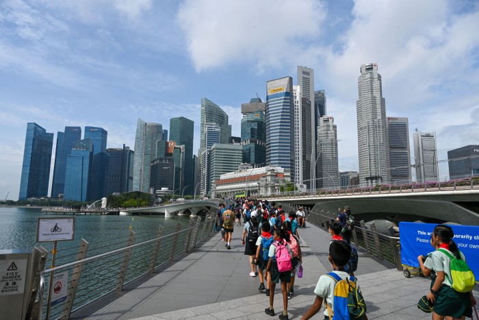 Children line up during a school trip at Marina Bay waterfront with tall buildings on the background