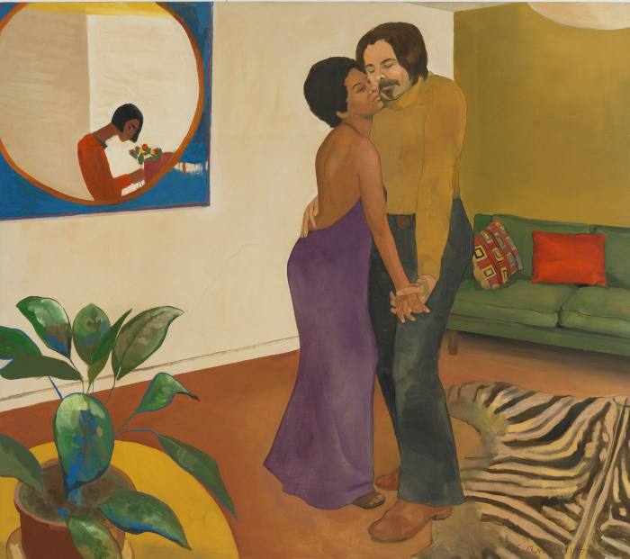 A woman in a long purple dress dances cheek to cheek with a man in a 1970s living room with a zebra-patterned rug