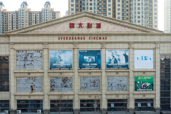 Posters fade on the facade of an Evergrande Cinemas building, with high-rise buildings in the background