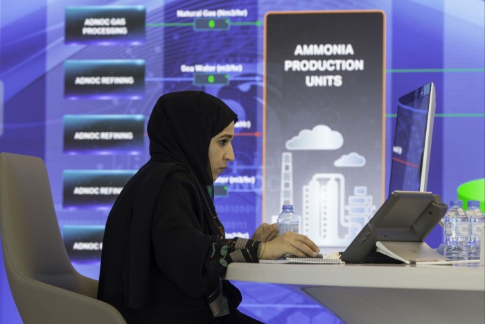 An employee works near a digital screen displaying ammonia production units at the Adnoc headquarters in Abu Dhabi