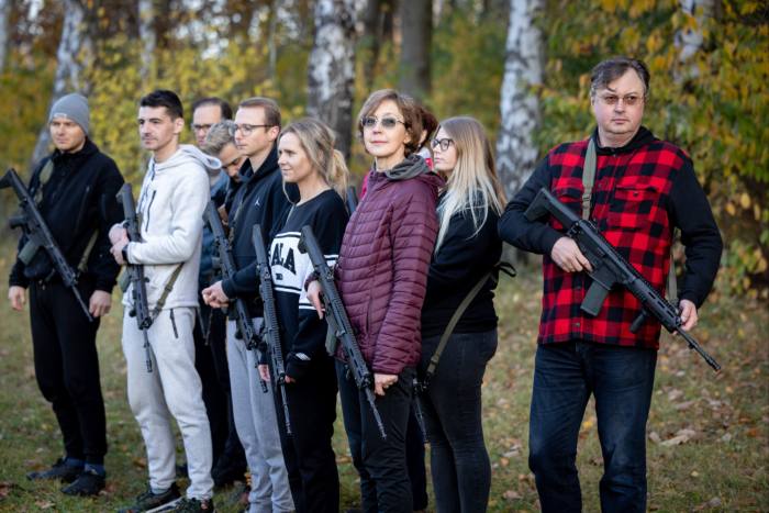 Men and women hold assault rifles