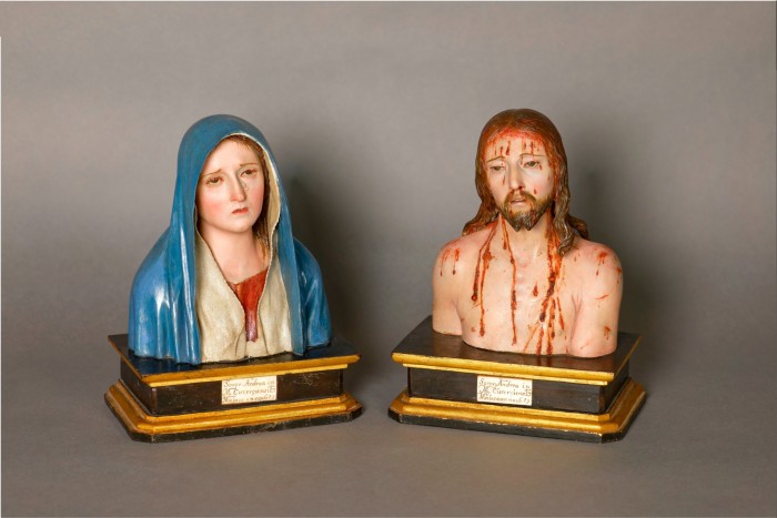 Two painted wooden busts, one of a woman in a blue robe, the other of a man with long brown hair bleeding rather heavily over his face