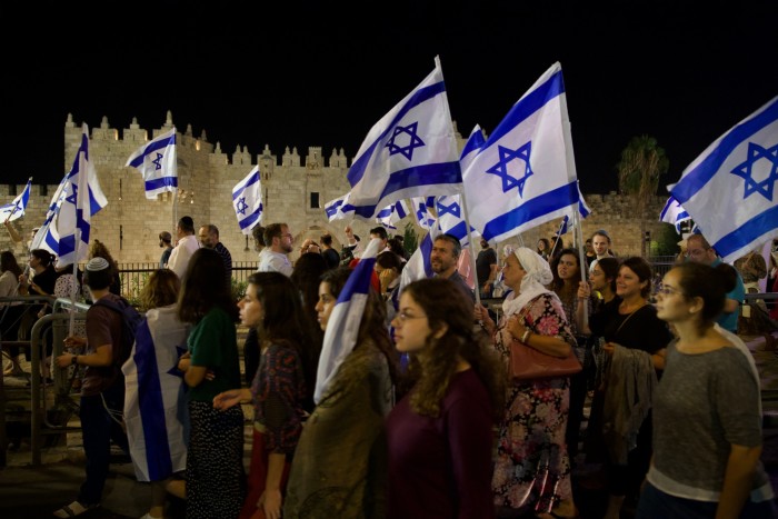 Activists march holding the Israeli flag near Damascus gate in Jerusalem