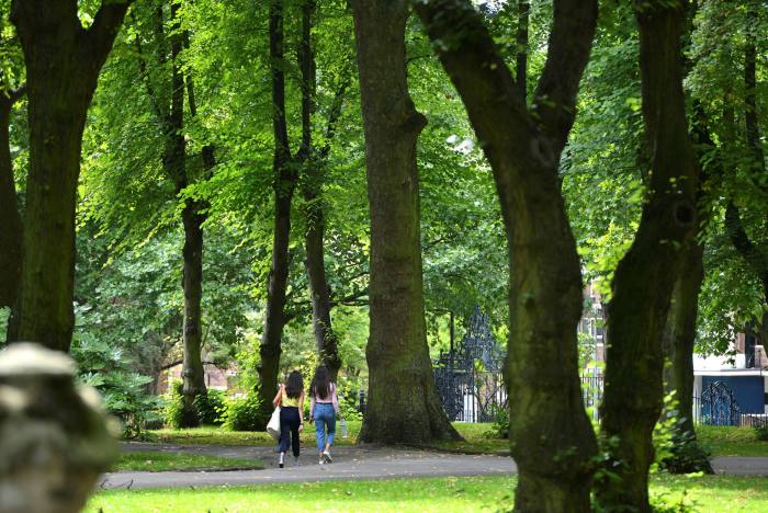 Two women walking through the trees in St Pancras Gardens