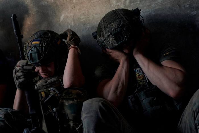 Ukrainian soldiers cover their ears as Russian tanks fire on their positions near Zaporizhia on Sunday