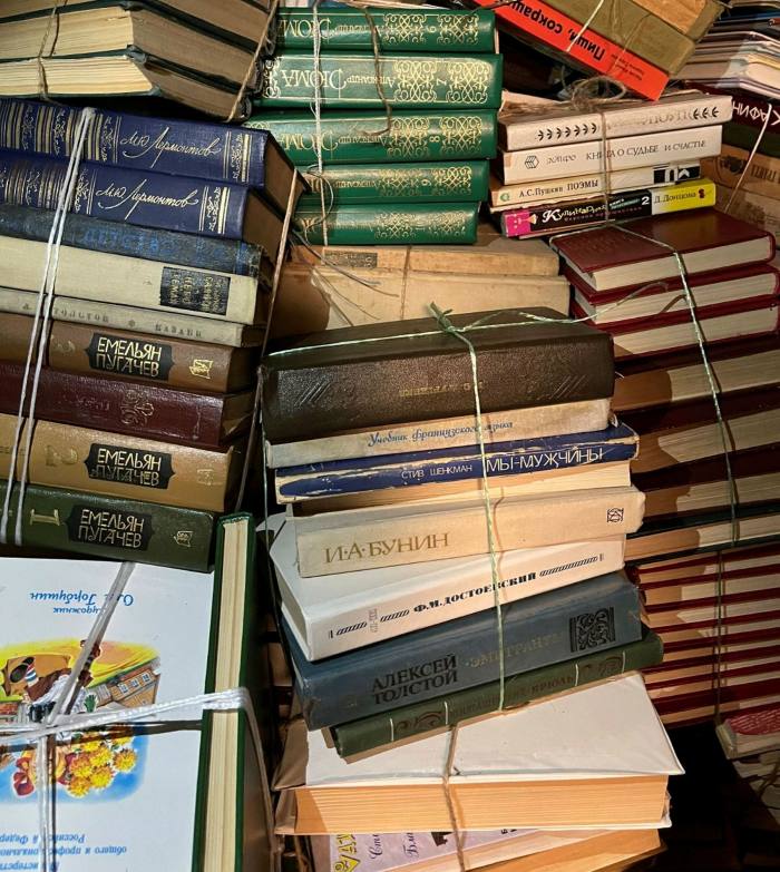Bundles of books, mainly hardbacks, with Russian writing on their covers and spines