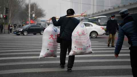 A migrant worker crosses a road after arriving on a long-distance bus in Beijing