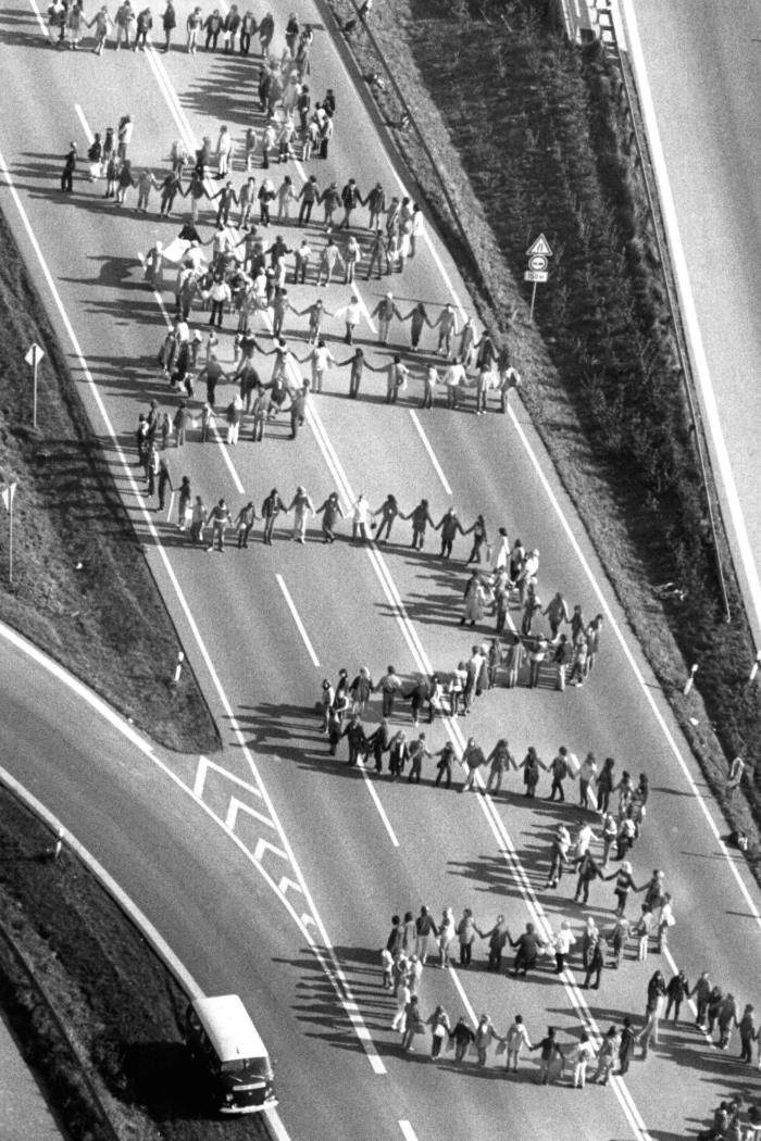 A line of people snake across a highway, seen from above