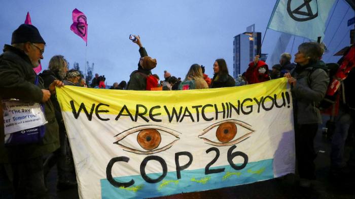 Protestors carry a sign reading, ‘We are watching you! COP26’