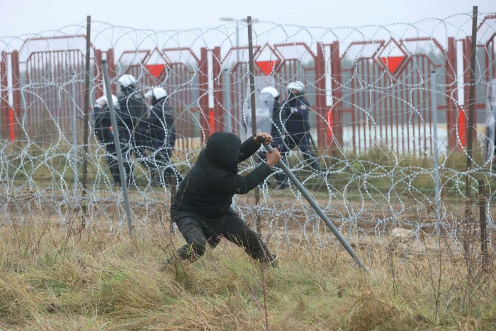A migrant attempts to destroy a fence during violent clashes at the Bruzgi-Kuznica border crossing on Tuesday