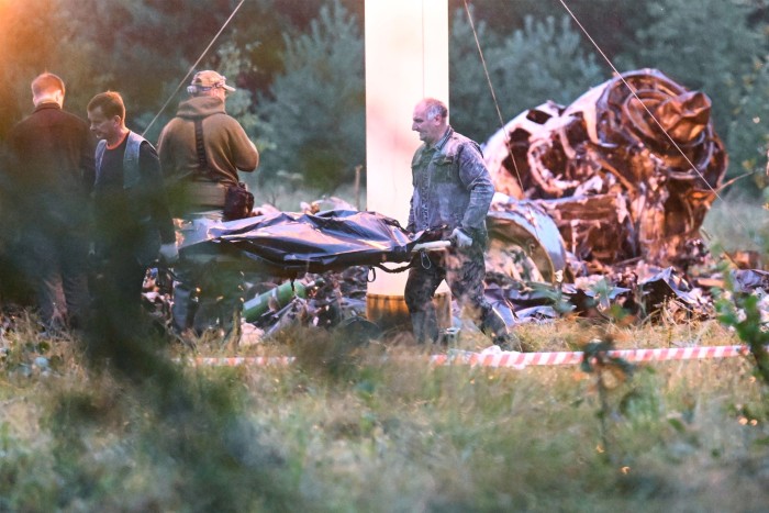 A body is carried away from the crash site