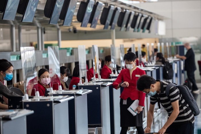 Cathay Pacific staff check in passengers in the departure hall at Hong Kong International Airport