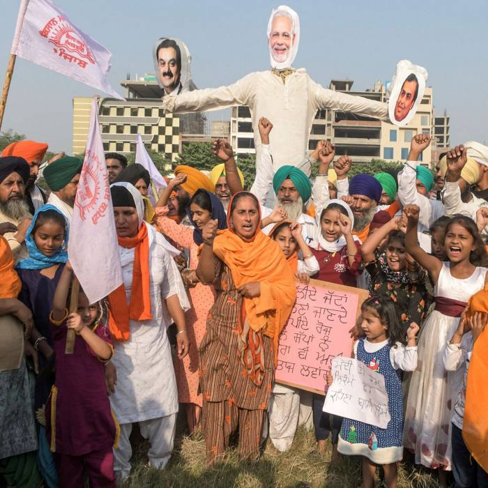 Farmers and their children shout slogans before burning effigies of Narendra Modi (C), Reliance Industries chairman Mukesh Ambani (R) and Gautam Adani following the recent passing of agriculture bills in parliament, in Amritsar