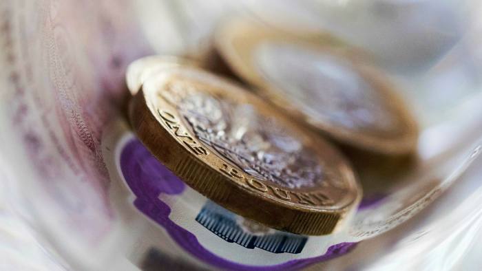 British £1 coins sit on a £20 note