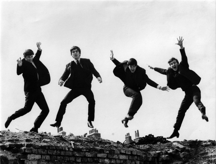 The four members of the Beatles leap into the air for a photograph, all wearing black boots 