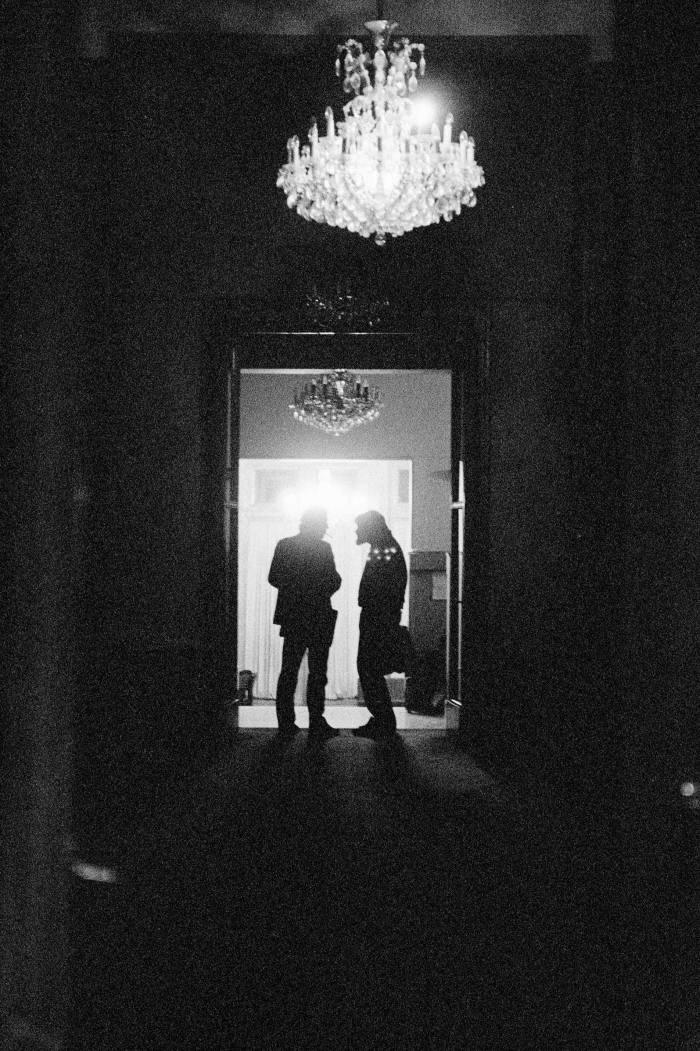 In this black-and-white photo from 1990 of two back-lit figures conferring in a corridor