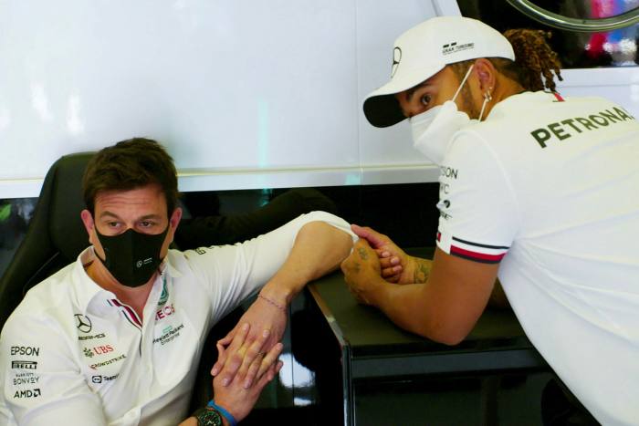 Two men wearing masks in the Formula 1 paddock looking dejected 