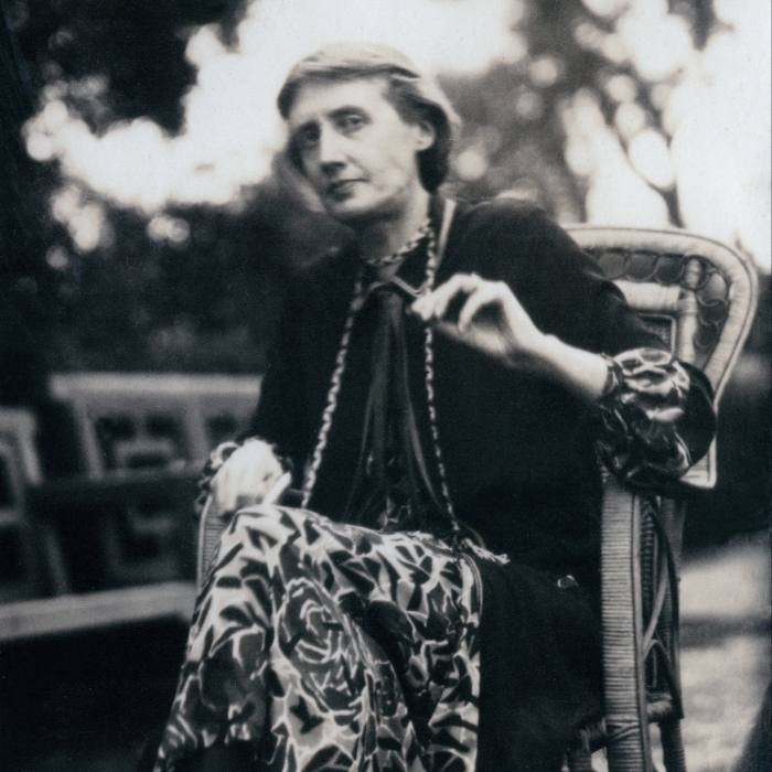 Black and white photograph of Virginia Woolf sitting outside in a wicker chair