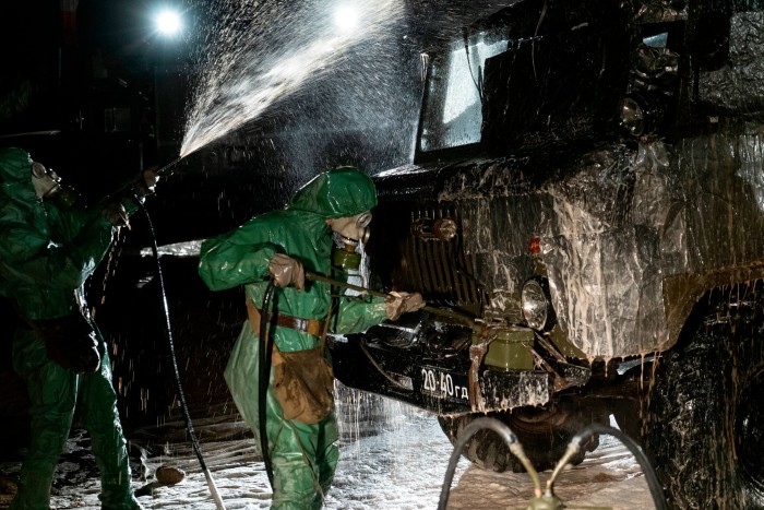 A scientist in a bio-hazard suit tending to machinery