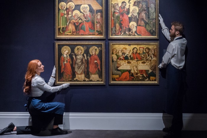 Technicians hold four 15th-century panels up for auction at Sotheby’s in London last week