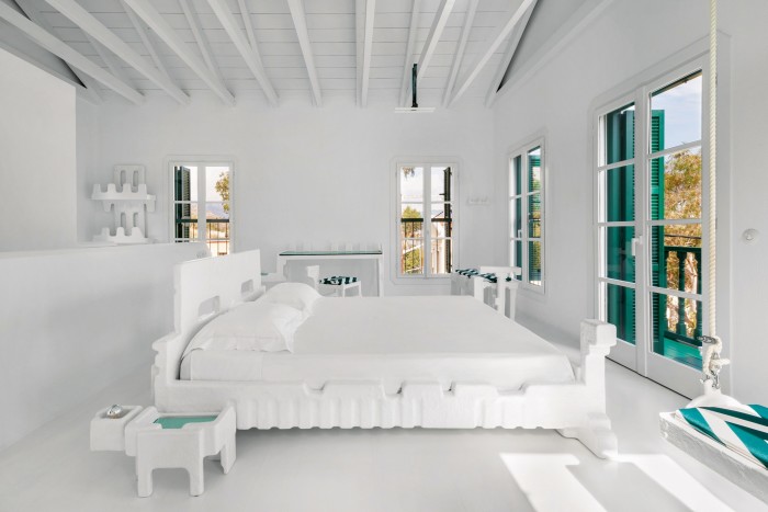 La stanza del soppalco ha un letto, un divano, uno specchio e una mensola nelle combinazioni di bianco, verde e rosa