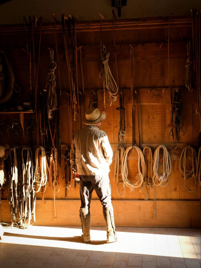 A man peruses horseriding gear in a stable