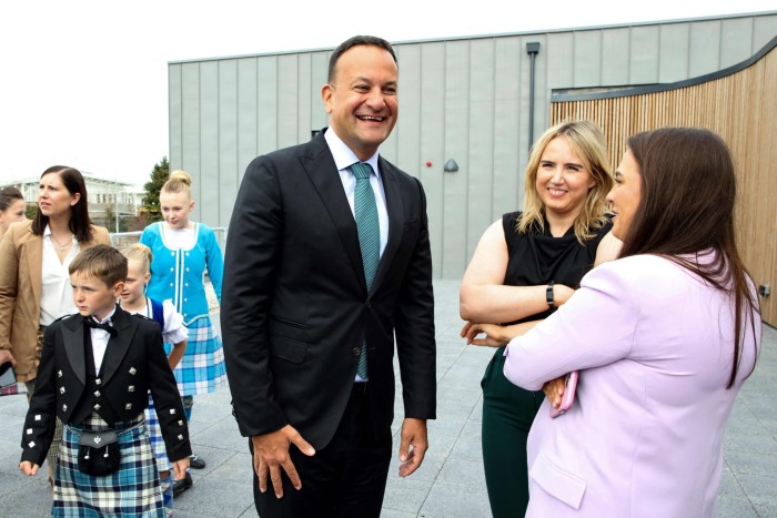 Ireland’s Prime Minister Leo Varadkar talking with two people, with children in the background