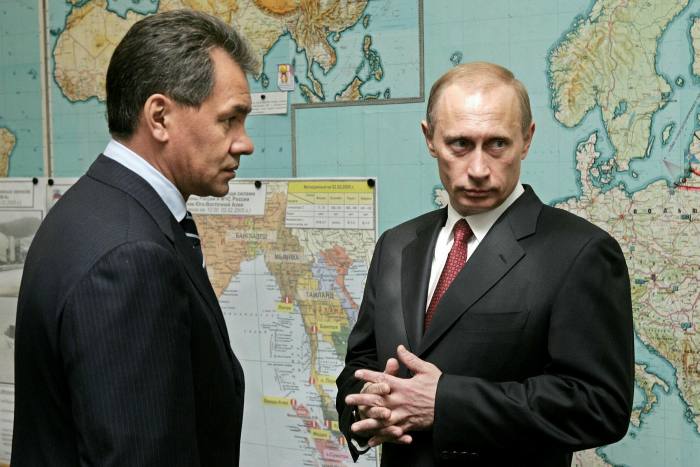 Putin and his emergencies minister stand in front of a large map of Europe in 2005