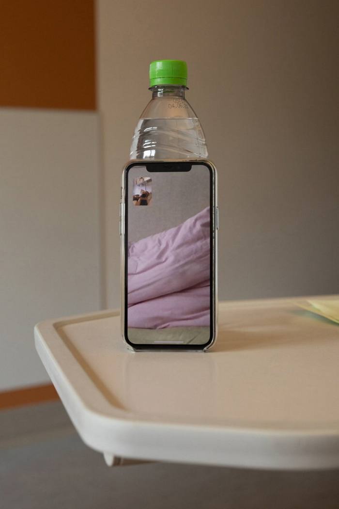 An iPhone leaning against a water bottle during a video call 