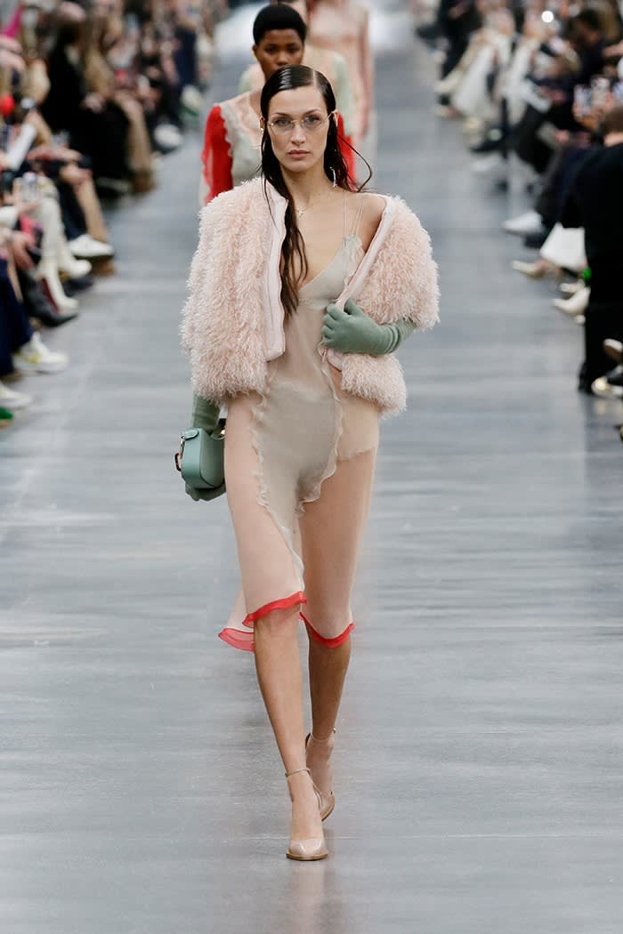 A young woman models an outfit that combines pink fur with see-through fabric