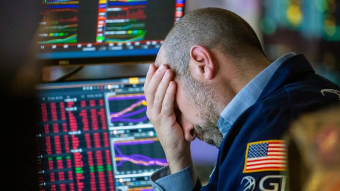 A trader on the New York Stock Exchange holds his head in his hands