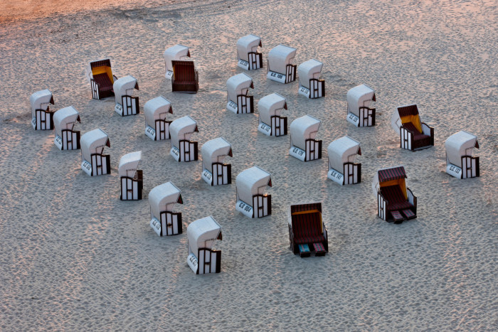 four rows of wicker sunbeds on the sand