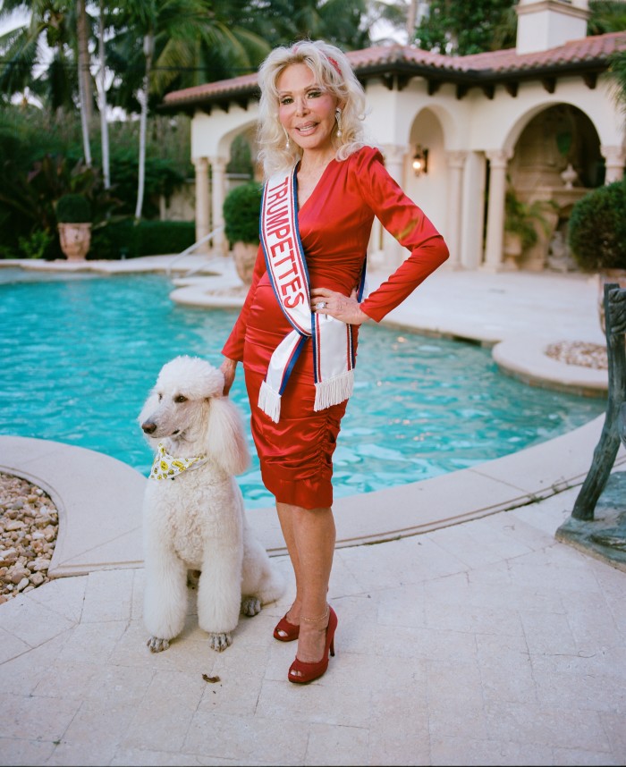 A woman in a red dress with a sash reading ‘Trumpette’ standing by her pool at her home in Palm Beach. She is a Donald Trump superfan
