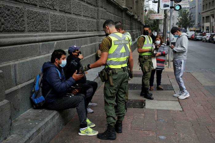 La policía revisa a los ciudadanos para obtener permiso para caminar por las calles de la capital chilena, Santiago, el lunes.