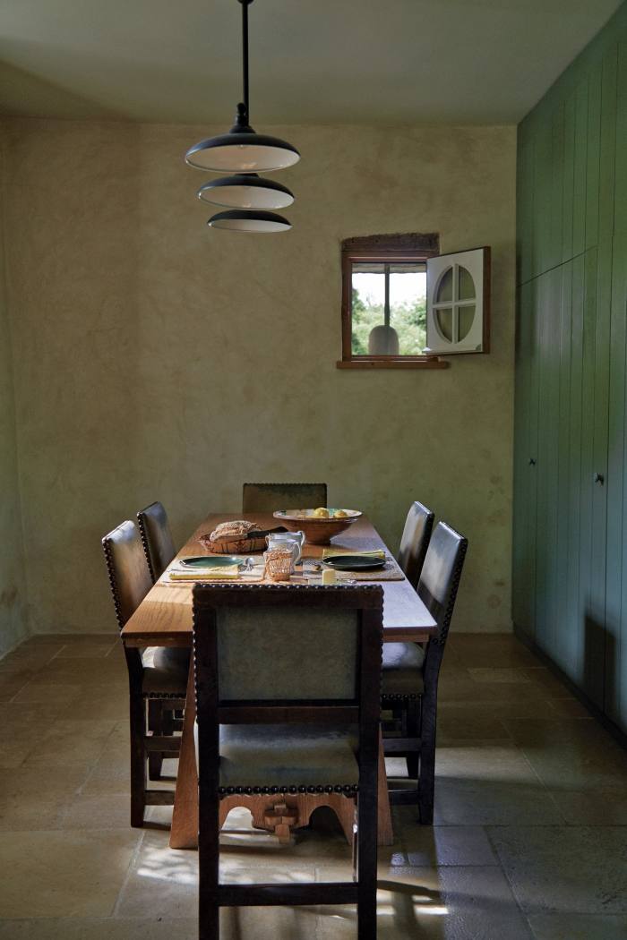 Part of the kitchen, the breakfast room has a long table from a monastery in the south of France, surrounded by suede-covered dining chairs