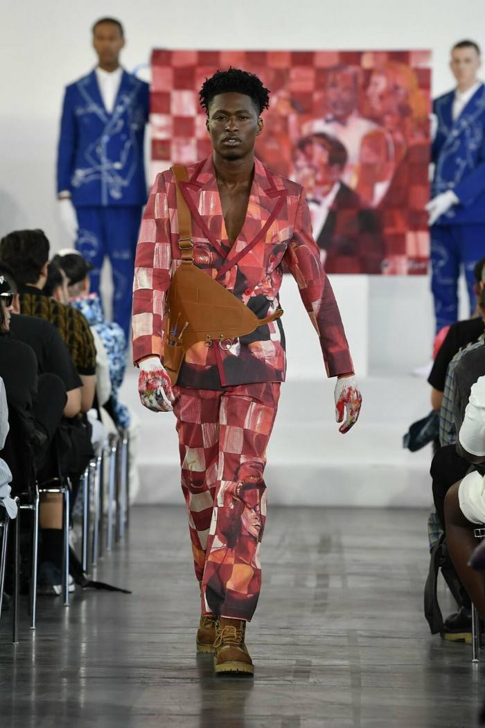 A male model walks the runway in a painted checkerboard jacket