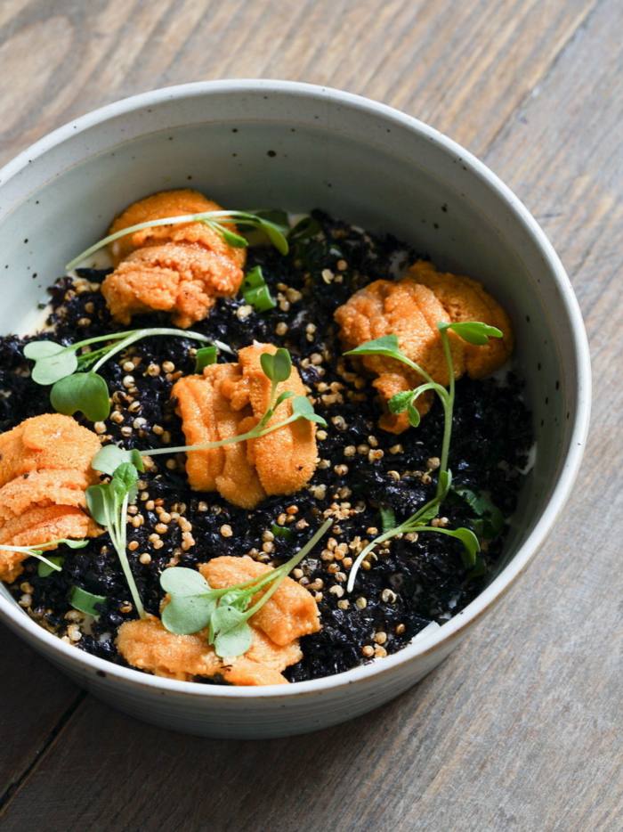 A bowl of sea urchins sitting on top of an egg custard covered with seaweed flakes at Atoboy