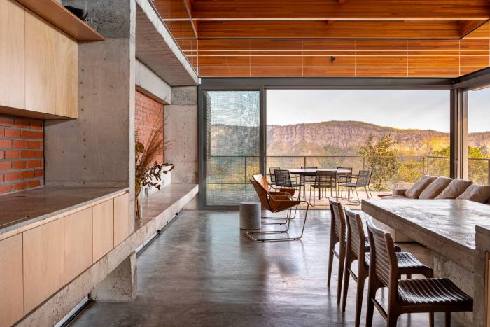 Pemandangan dalaman dapur moden, yang mempunyai meja makan panjang, kerusi dan tingkap gelangsar yang besar