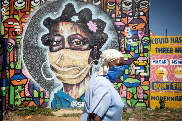 A woman in Soweto, South Africa walks in front of a graffiti art work educating local residents about the dangers of coronavirus