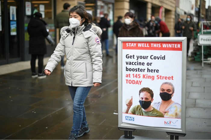 A woman walks past a ‘wear a mask’ sign outside a pop-up vaccination centre for the Covid-19 vaccine in London