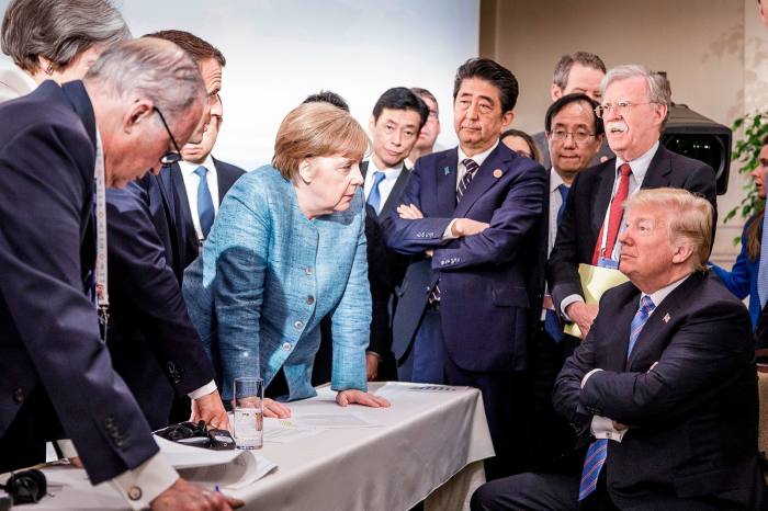 German Chancellor Angela Merkel deliberates with US president Donald Trump on the sidelines of the official agenda on the second day of the G7 summit on June 9, 2018 in Charlevoix, Canada. Also pictured are (L-R) Larry Kudlow, director of the US National Economic Council, Theresa May, UK prime minister, Emmanuel Macron, French president, Angela Merkel, Yasutoshi Nishimura, Japanese deputy chief cabinet secretary, Shinzo Abe, Japan prime minister, Kazuyuki Yamazaki, Japanese senior deputy minister for foreign affairs, John Bolton, US national security adviser