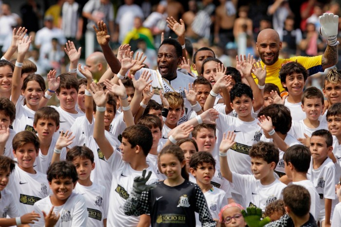 Pelé y su hijo Edson Cholbi do Nascimento saludan con niños durante la celebración del centenario del equipo en Santos, Brasil, el 14 de abril de 2012.