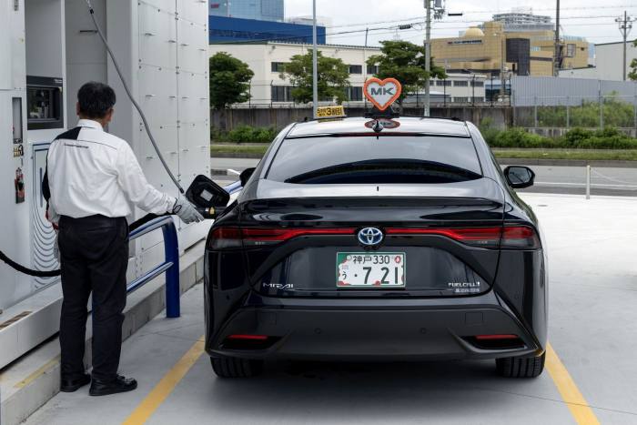 An employee fills up a Toyota hydrogen fuel cell vehicle in Kobe, Japan